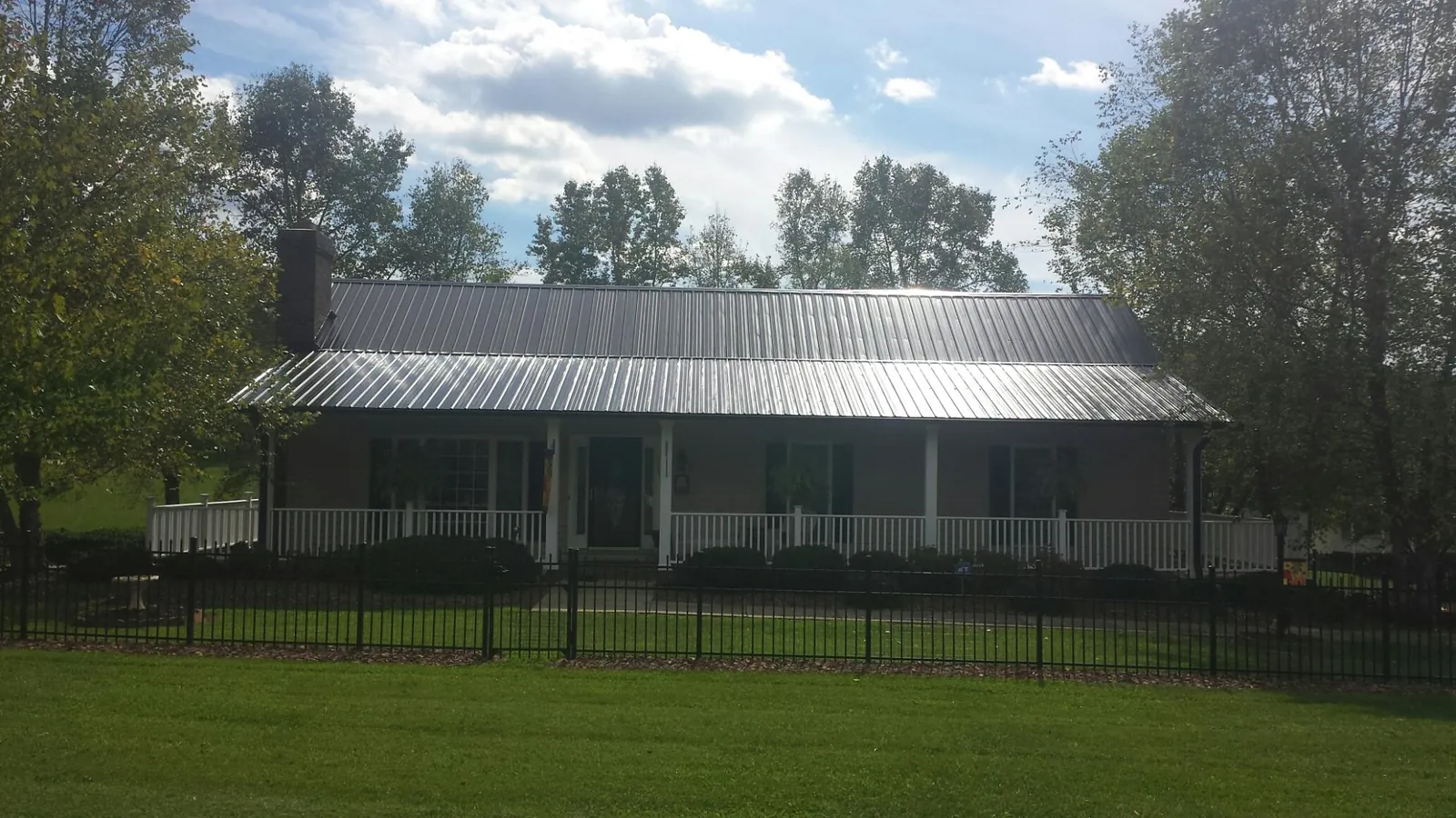Gray metal roof on a brick ranch with a full width front porch — Gutter Guard Installation work by our crew in Braxton